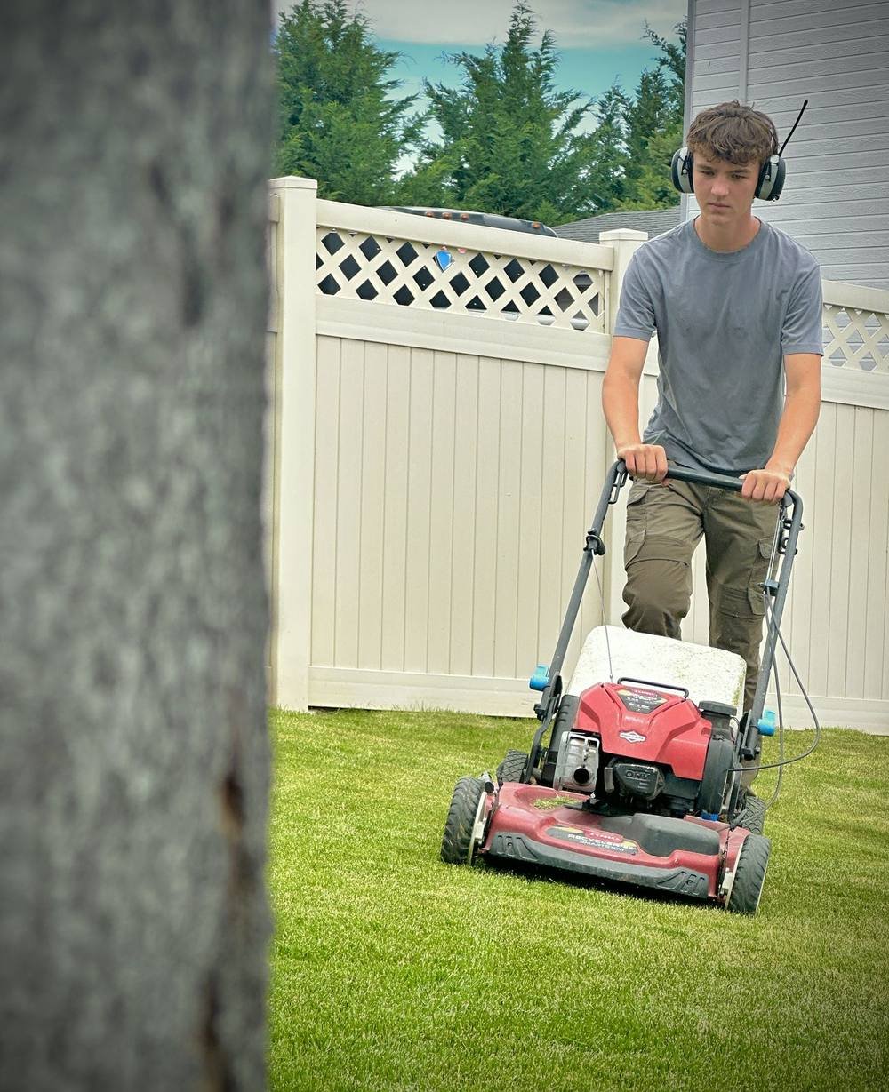 Greencrest owner mowing a client's backyard